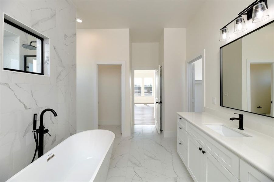 Full bath featuring marble finish floor, a soaking tub, plenty of natural light, and vanity