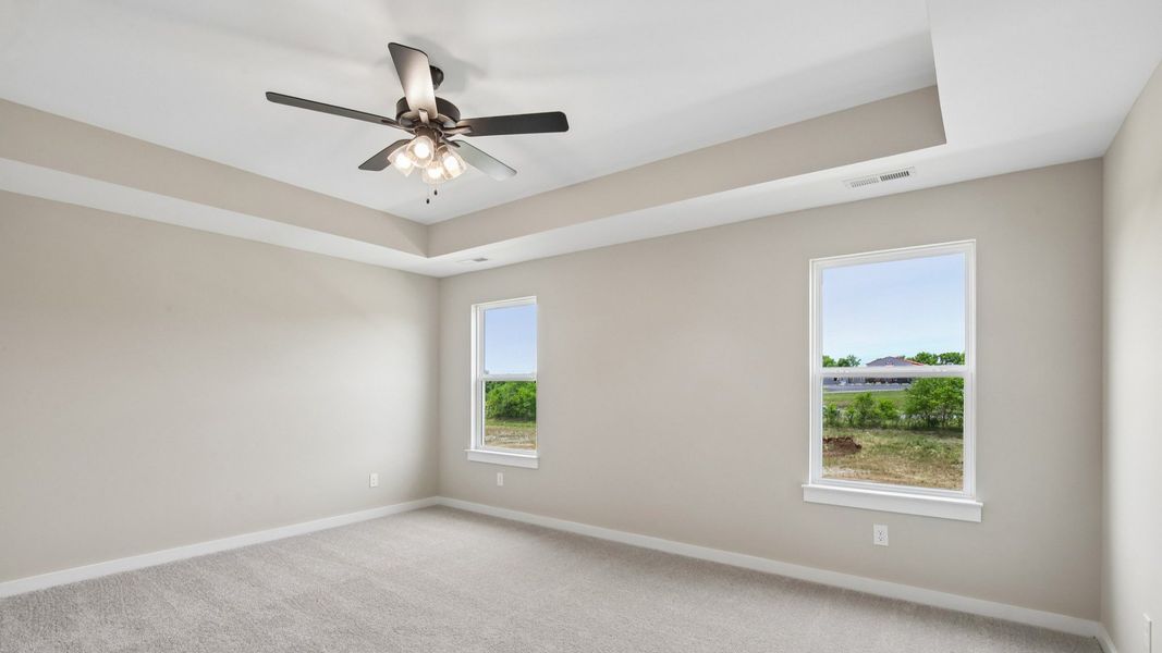 Bedroom with tray ceiling, windows, and ceiling fan Bedroom with tray ceiling, windows, and ceiling fan