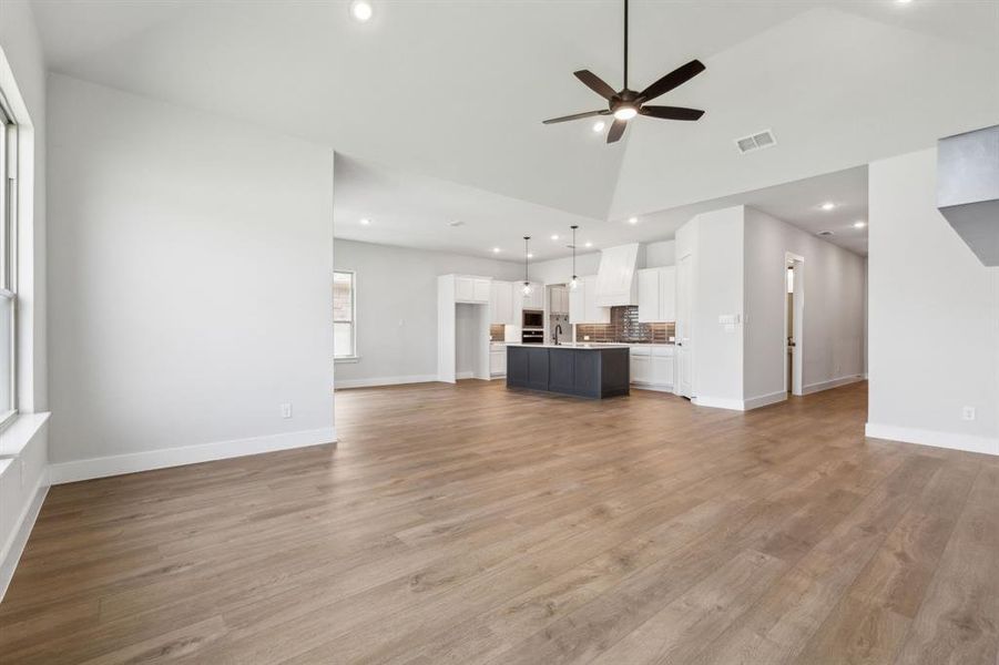 Unfurnished living room featuring light hardwood / wood-style floors, high vaulted ceiling, and ceiling fan