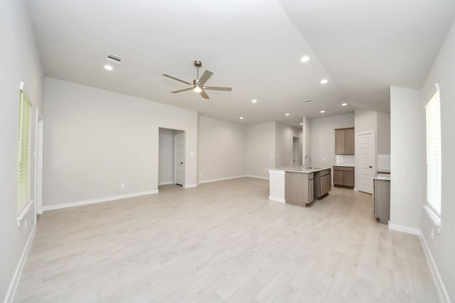 Welcome family and guests to your charming living room! With its high ceilings, recessed lighting, ceiling fan, custom paint, beautiful flooring, and large windows that let in abundant natural light, this room is perfect for gatherings. Sample photo of completed home with similar floor plan. Actual colors and selections may vary.