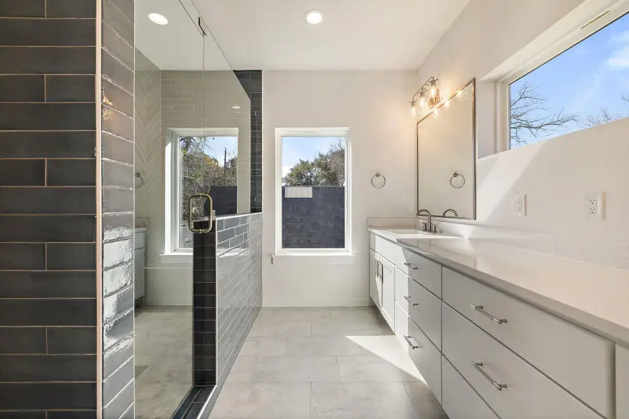 Primary Bathroom with recessed lighting, baseboards, tiled shower, and vanity