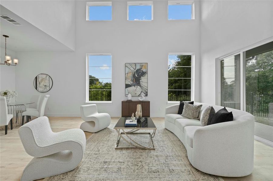 Living area featuring a towering ceiling, a chandelier, and wood finished floors Living area featuring a towering ceiling, a chandelier, and wood finished floors
