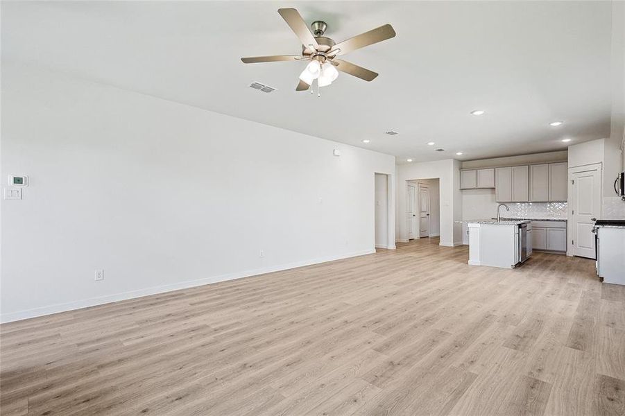 Unfurnished living room featuring light hardwood / wood-style flooring, ceiling fan, and sink