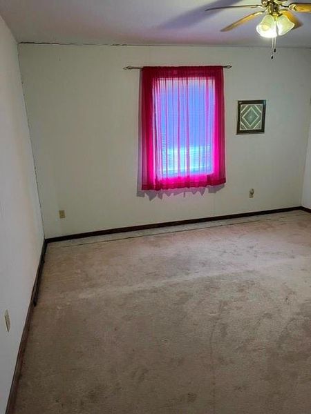 Carpeted room with a window, baseboard trim, and a ceiling fan Carpeted room with a window, baseboard trim, and a ceiling fan