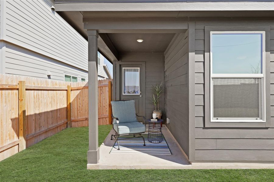 A cozy covered patio offers the perfect shaded retreat for outdoor relaxation, overlooking a private, fully-fenced backyard with a low-maintenance lawn