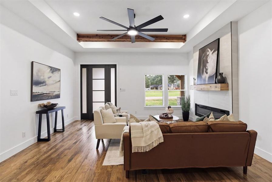 Living space featuring wood-finish flooring, a modern linear fireplace with a light-toned tile surround, and a natural wood mantel