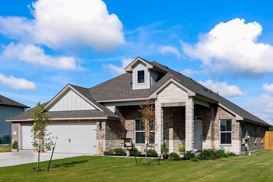 View of front of house featuring a shingled roof, stone siding, an attached garage, and covered porch