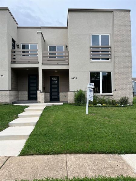 Modern townhouse exterior featuring a stucco and brick facade
