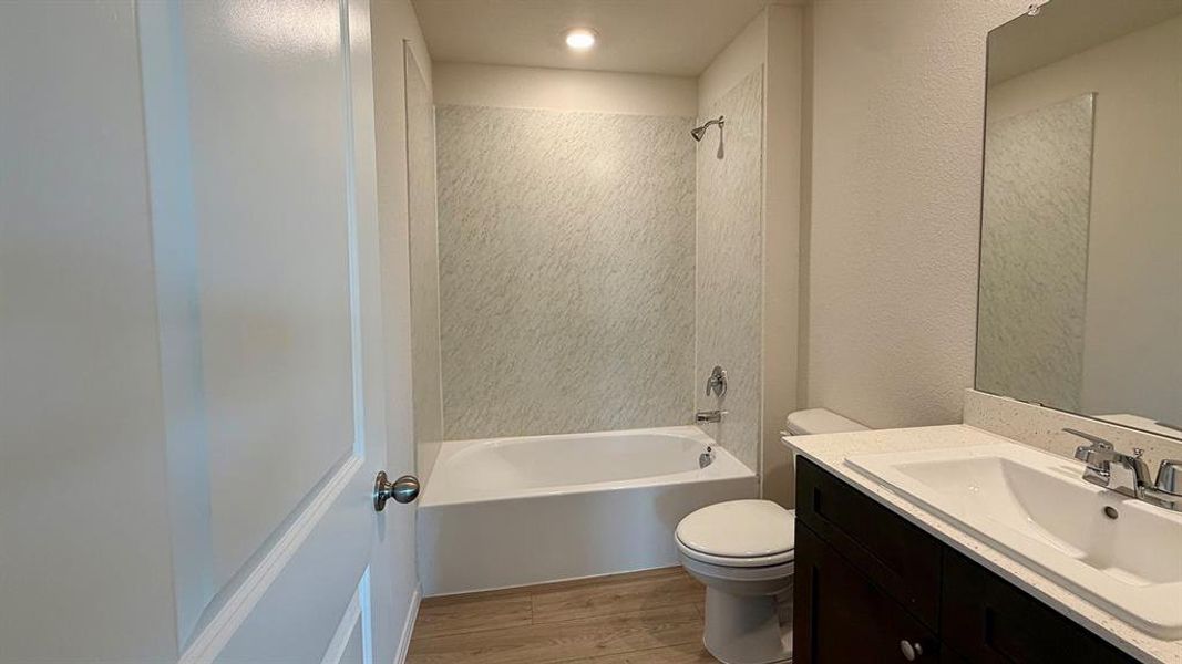 Bathroom featuring a dark wood-finish vanity with a light countertop, integrated sink, and a large wall-mounted mirror