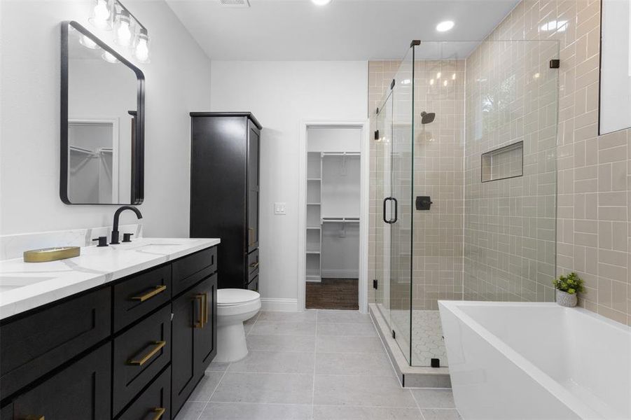 Bathroom with a stall shower, double vanity, a walk in closet, a tub, and recessed lighting Bathroom with a stall shower, double vanity, a walk in closet, a tub, and recessed lighting