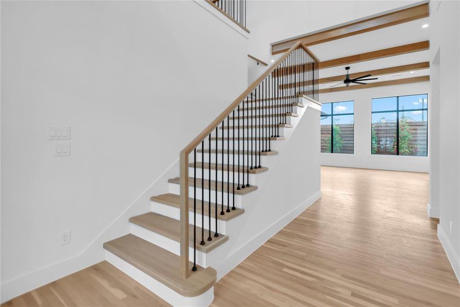 Stairs featuring wood finished floors and ceiling fan Stairs featuring wood finished floors and ceiling fan