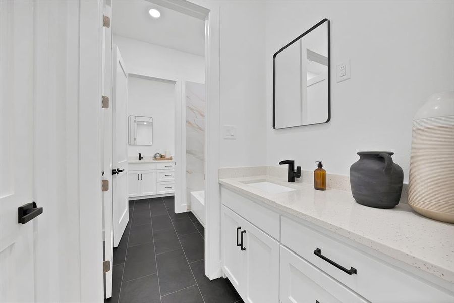 Bathroom featuring a white vanity with a light-toned countertop, a black framed mirror, and a black faucet