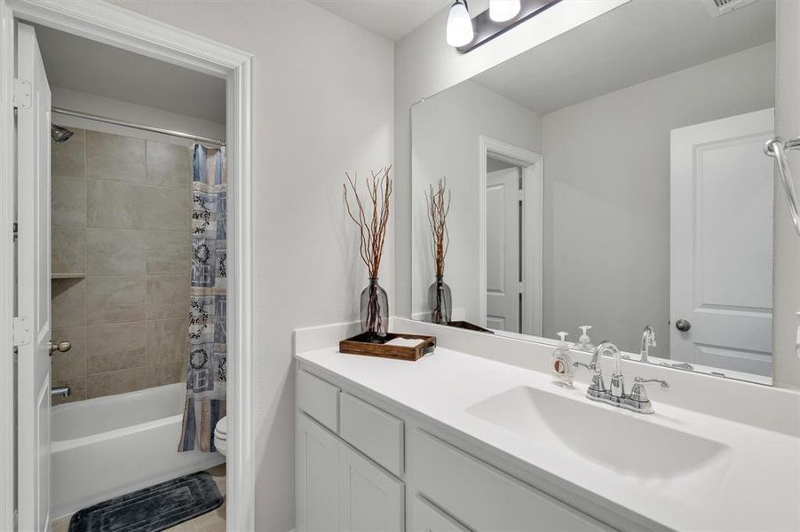Bathroom featuring a white vanity with an integrated sink, polished chrome faucet, and a large mirror