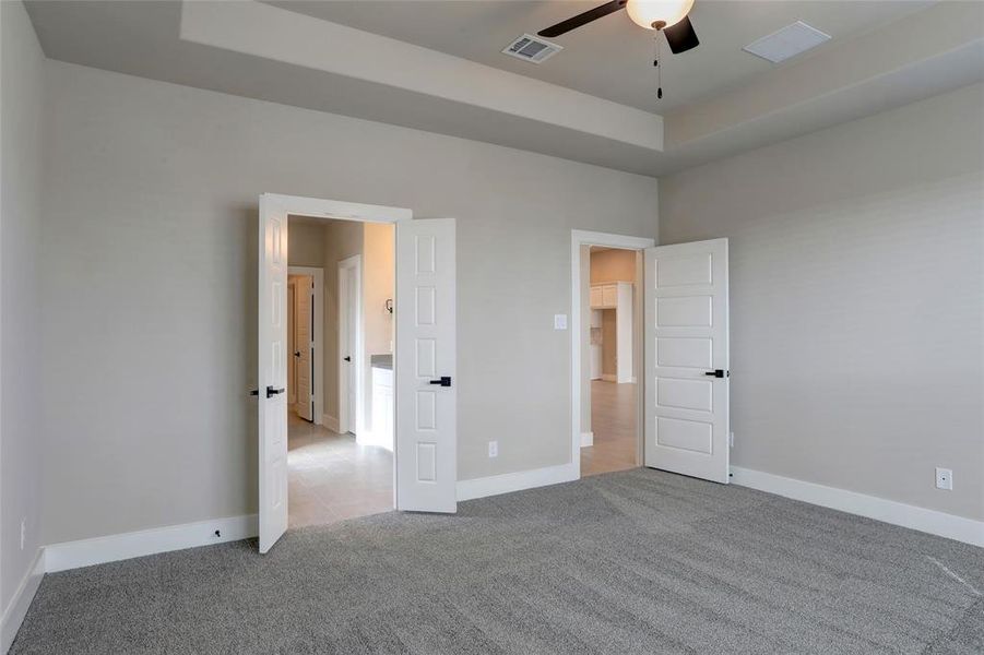 Unfurnished bedroom featuring light carpet and a tray ceiling