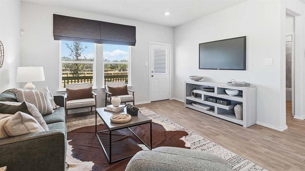 Open-concept living area featuring light wood-finish flooring and ample natural light through large windows