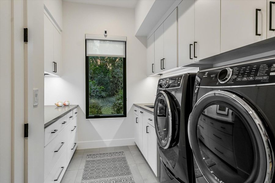 Laundry room featuring cabinet space, light tile patterned floors, and washing machine and clothes dryer Laundry room featuring cabinet space, light tile patterned floors, and washing machine and clothes dryer