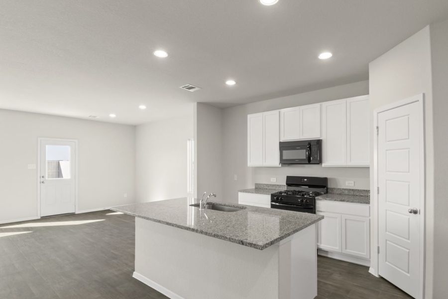 Image of a kitchen with white cabinets, granite counter tops, a center island, black appliances and a corner pantry Image of a kitchen with white cabinets, granite counter tops, a center island, black appliances and a corner pantry