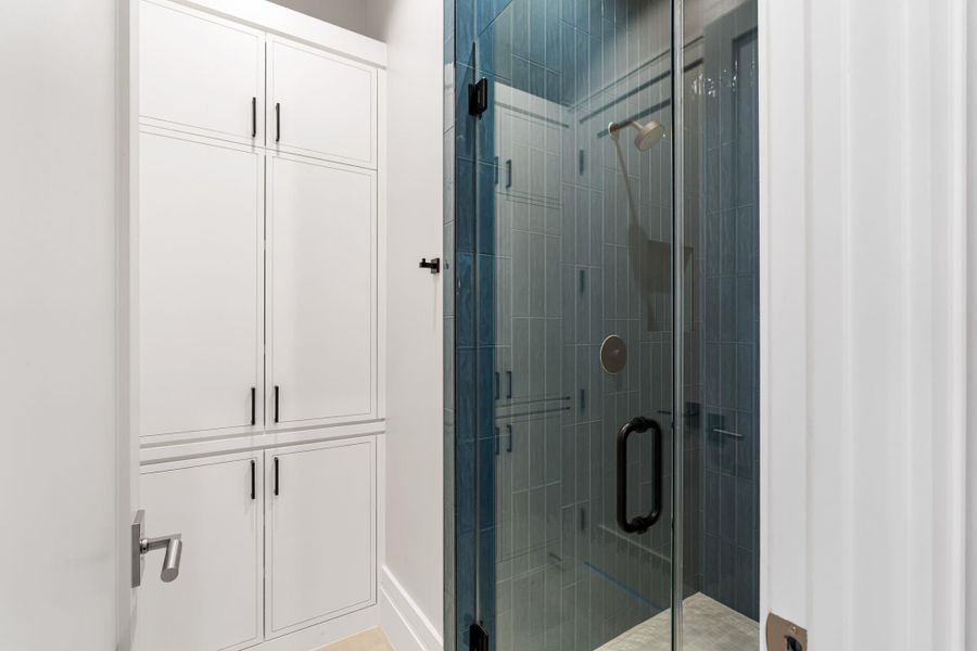 Guest bath with glass frame shower, abundant cabinetry and chic tile design.