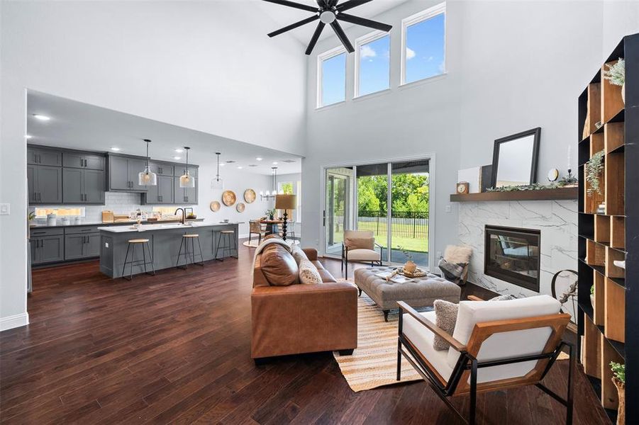 Living room featuring a fireplace, a ceiling fan, and dark wood-style flooring