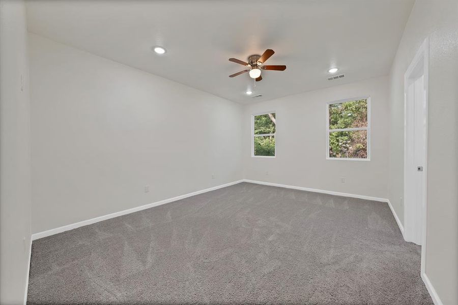 Carpeted empty room featuring ceiling fan and recessed lighting