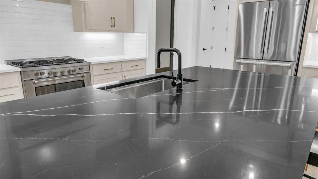 Kitchen with stainless steel appliances, a sink, decorative backsplash, white cabinets, and light stone countertops Kitchen with stainless steel appliances, a sink, decorative backsplash, white cabinets, and light stone countertops