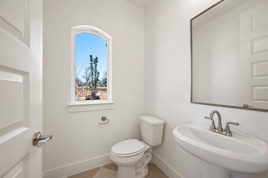 Half bathroom with toilet and baseboards