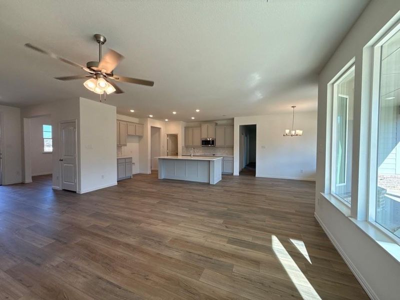Unfurnished living room featuring dark wood-type flooring, ceiling fan, recessed lighting, and a chandelier