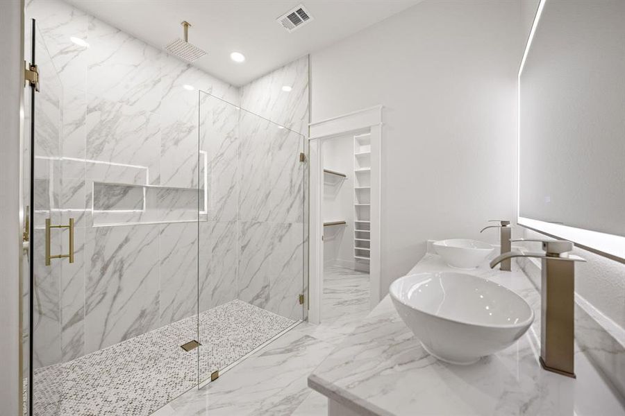 Walk-in shower featuring large format marble-look tile, a rain shower head, and built-in niches Walk-in shower featuring large format marble-look tile, a rain shower head, and built-in niches
