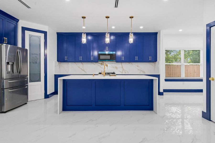 View of the contemporary kitchen that blends style and function with bold blue cabinetry, a central island topped with a quartz countertop, and sleek stainless steel appliances. Elegant pendant lighting and a dedicated pantry door add convenience and charm, while the window fills the space with bright natural light. View of the contemporary kitchen that blends style and function with bold blue cabinetry, a central island topped with a quartz countertop, and sleek stainless steel appliances. Elegant pendant lighting and a dedicated pantry door add convenience and charm, while the window fills the space with bright natural light.
