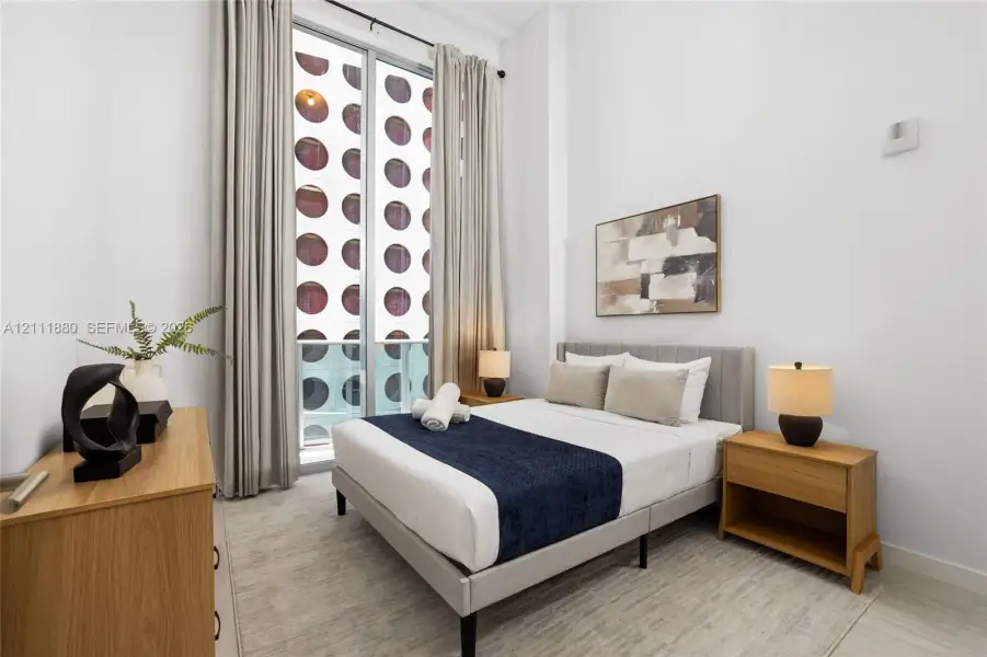 Floor-to-ceiling windows featuring neutral drapery, high ceilings, and light-toned tile flooring
