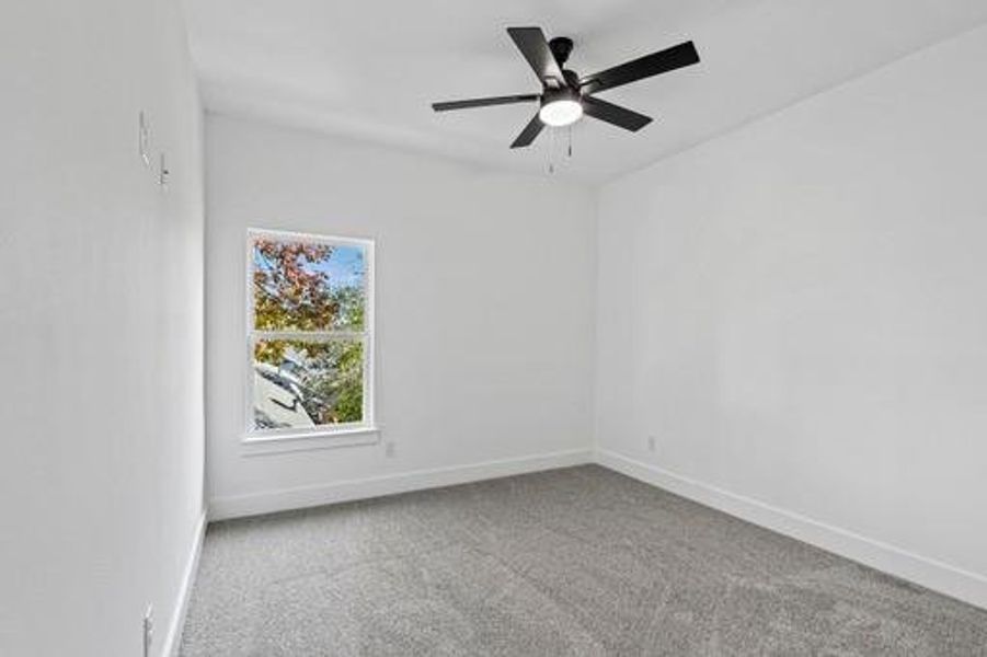 Spare room featuring carpet and ceiling fan