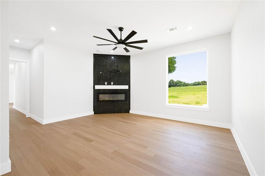 Unfurnished living room featuring light wood-type flooring, a fireplace, baseboards, a ceiling fan, and recessed lighting Unfurnished living room featuring light wood-type flooring, a fireplace, baseboards, a ceiling fan, and recessed lighting