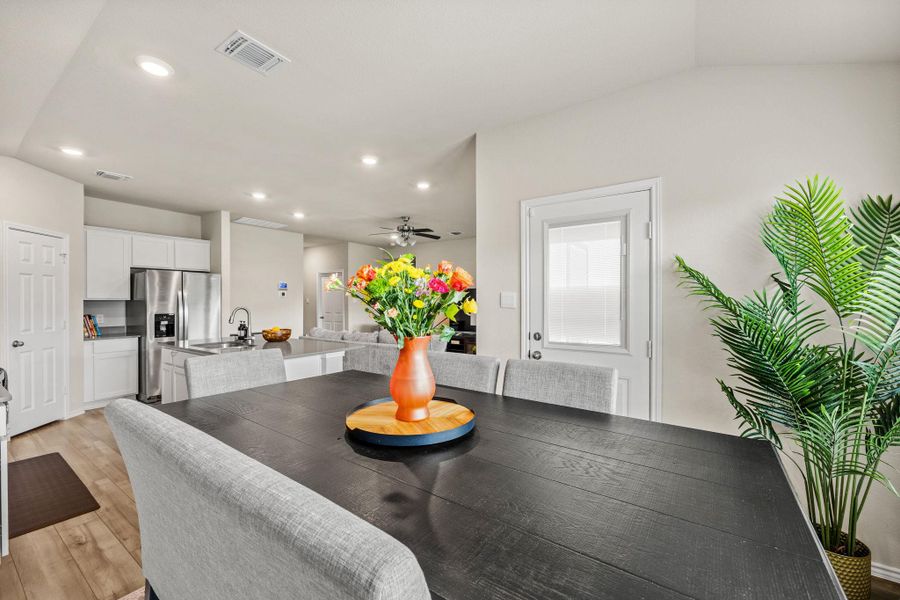 An open concept kitchen and dining space with light wood flooring provides seamless flow for entertaining.