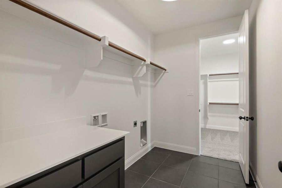 Washroom with washer hookup, hookup for an electric dryer, laundry area, dark tile patterned floors, and baseboards