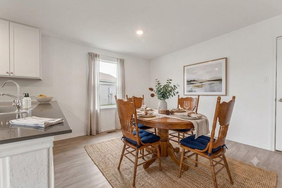 A well-lit dining area features light wood flooring and a classic dining set, perfect for everyday meals.