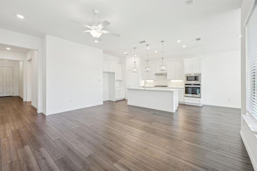 Unfurnished living room featuring ceiling fan, dark hardwood / wood-style flooring, and sink