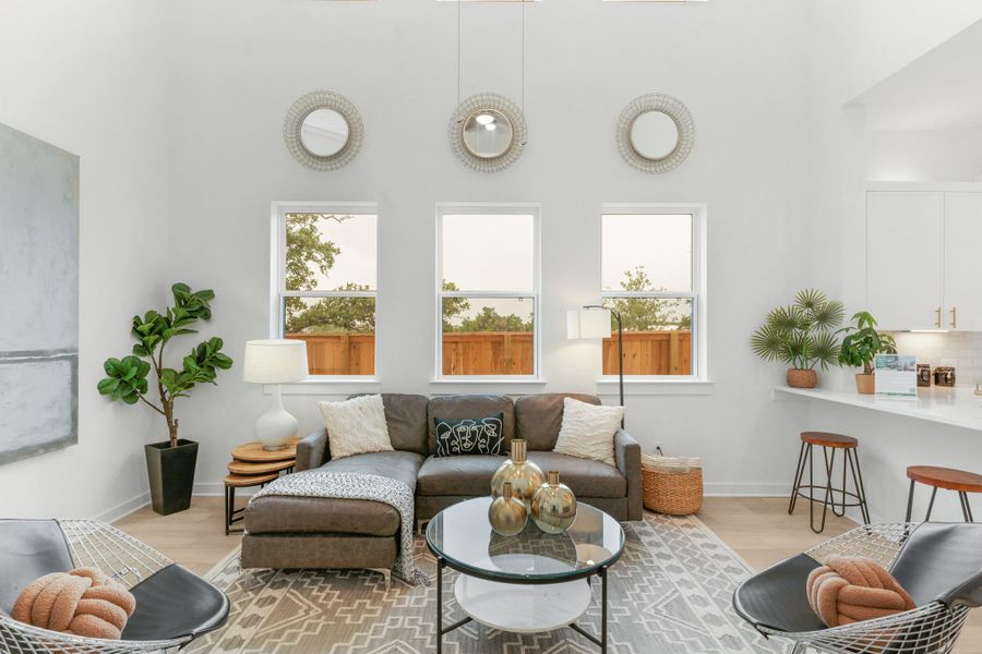 Living area with a towering ceiling, light wood-style flooring, and baseboards