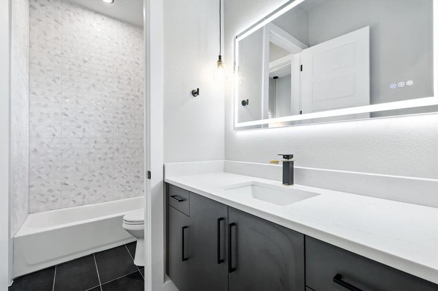 Bathroom featuring vanity, dark tile patterned floors, and shower / bath combination Bathroom featuring vanity, dark tile patterned floors, and shower / bath combination