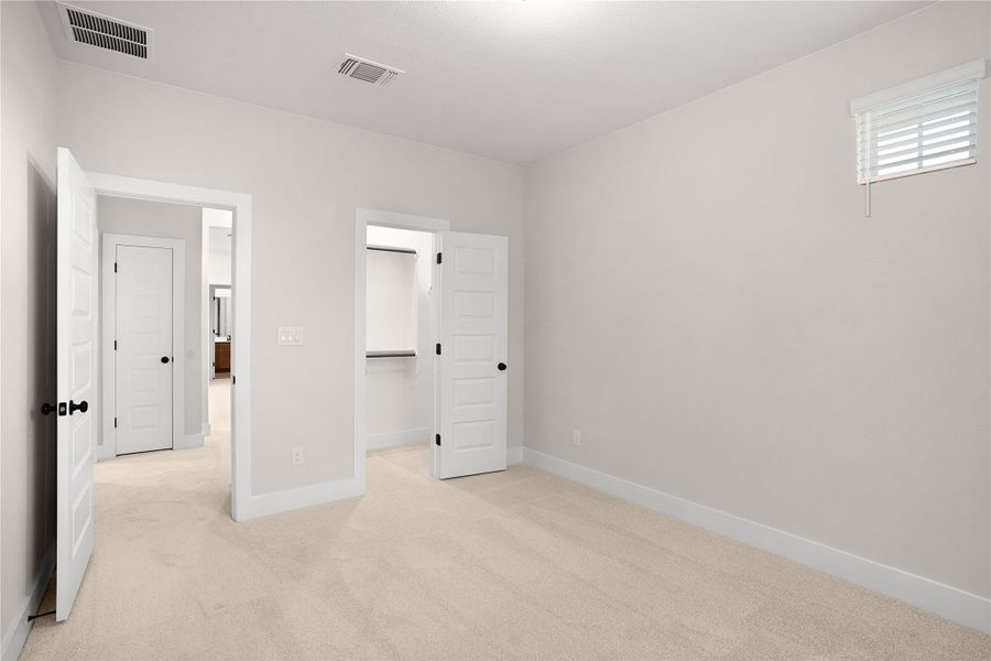 A well-lit bedroom features plush carpeting and convenient closet access. A well-lit bedroom features plush carpeting and convenient closet access.