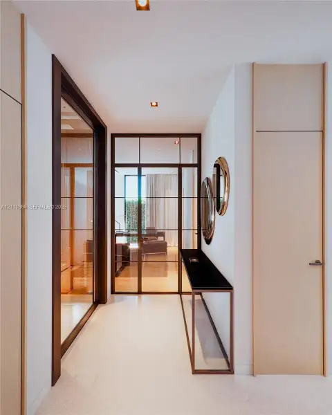 Hallway featuring full-height light wood doors, a metal-framed glass partition with a paneled door, flush-mount ceiling lighting, and a built-in wall-mounted console with a dark stone surface Hallway featuring full-height light wood doors, a metal-framed glass partition with a paneled door, flush-mount ceiling lighting, and a built-in wall-mounted console with a dark stone surface