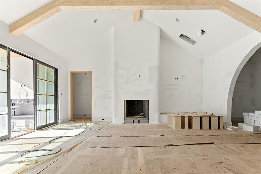 Unfurnished living room featuring high vaulted ceiling, beam ceiling, and hardwood / wood-style floors