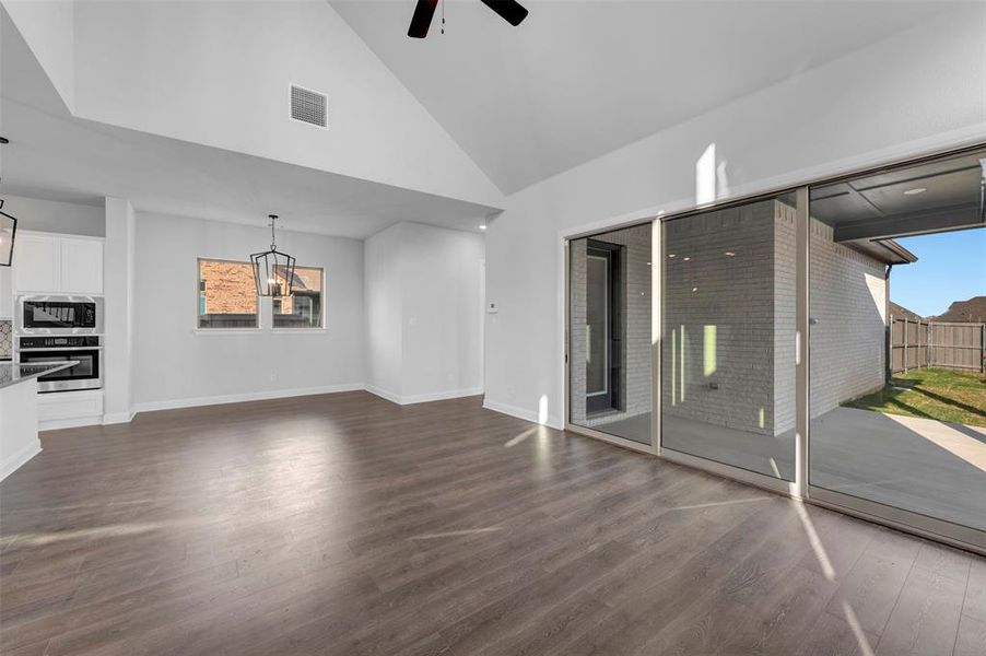 Unfurnished living room with lofted ceiling, dark wood-type flooring, and a ceiling fan Unfurnished living room with lofted ceiling, dark wood-type flooring, and a ceiling fan