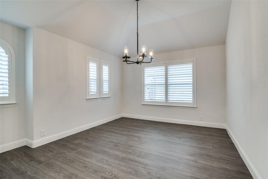 Dining room featuring a notable chandelier, dark wood-type flooring and plantation shutters!