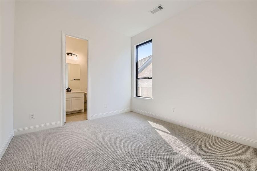 Unfurnished bedroom with light carpet and connected bathroom