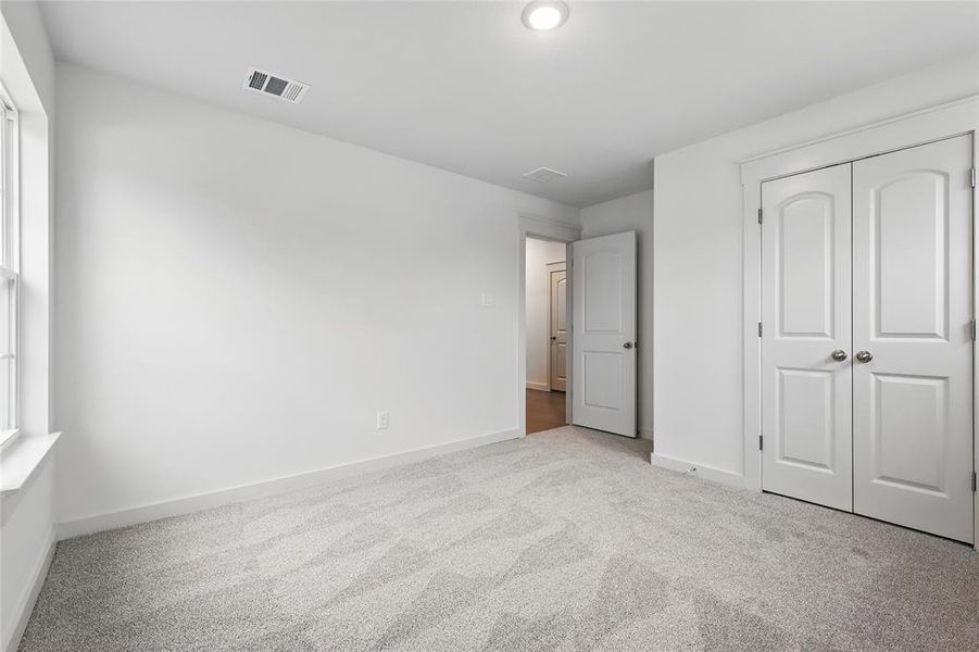 Unfurnished bedroom featuring light carpet and a closet Unfurnished bedroom featuring light carpet and a closet