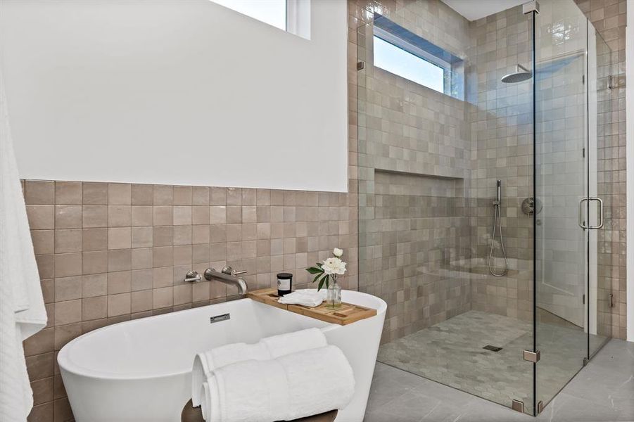 Bathroom with tile patterned flooring, tile walls, and shower with separate bathtub