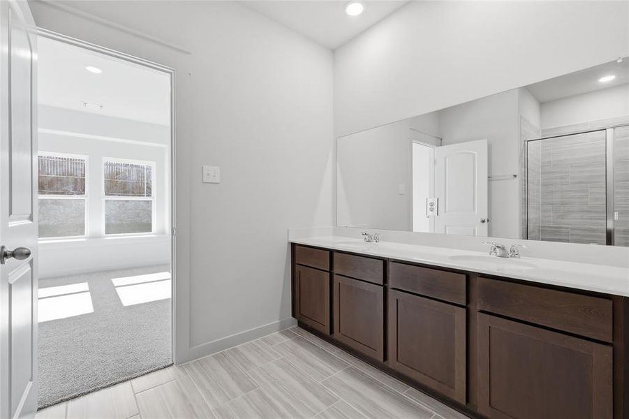 Dual sink vanity with dark wood-finish cabinetry, a full-width mirror, and tile flooring