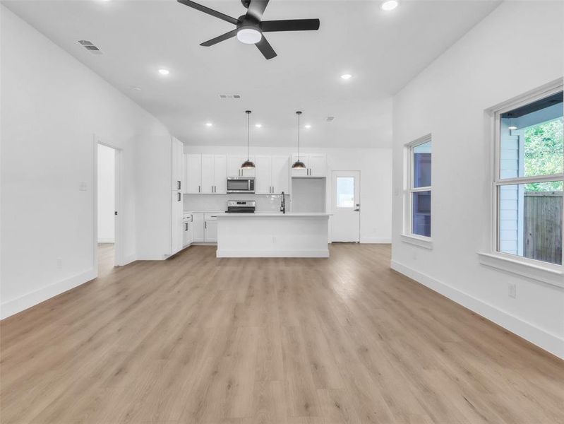 Unfurnished living room with a ceiling fan, baseboards, recessed lighting, and light wood-style flooring Unfurnished living room with a ceiling fan, baseboards, recessed lighting, and light wood-style flooring