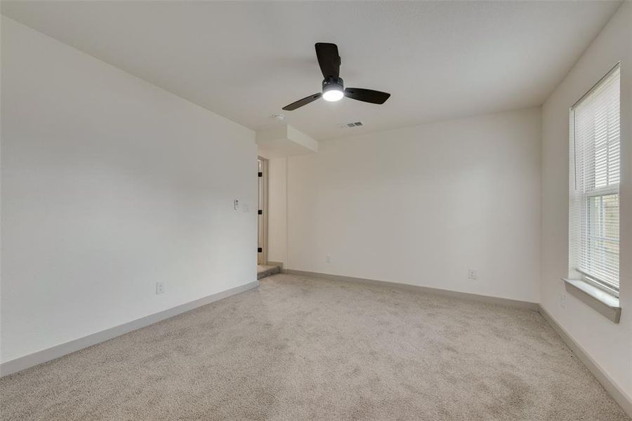 Carpeted empty room featuring ceiling fan