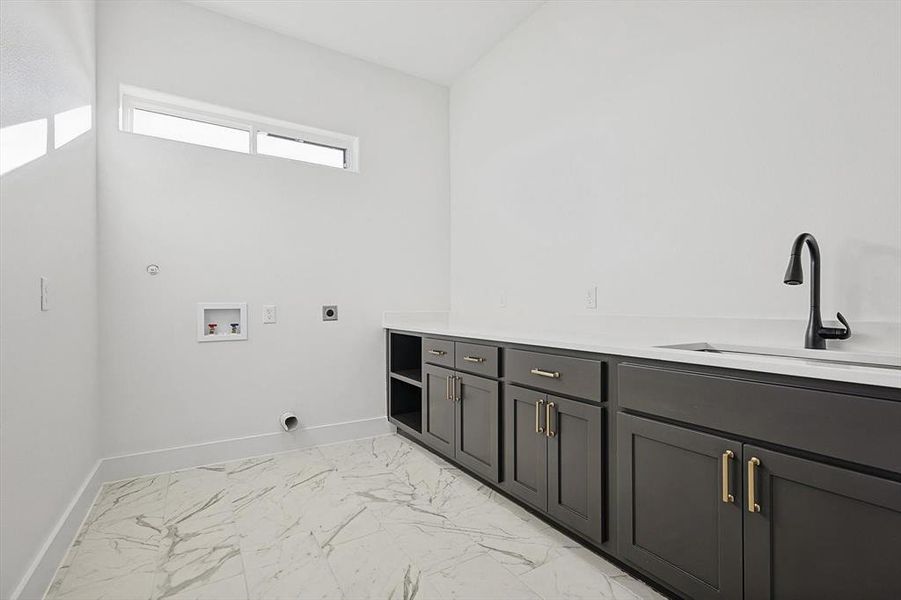 Clothes washing area with electric dryer hookup, sink, cabinets, and washer hookup